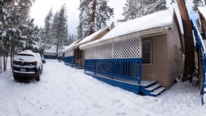 Een besneeud gebied buiten met een auto en een chalet.