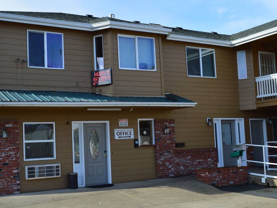 A two-story motel with a front office, a balcony, and a brick accent wall.
