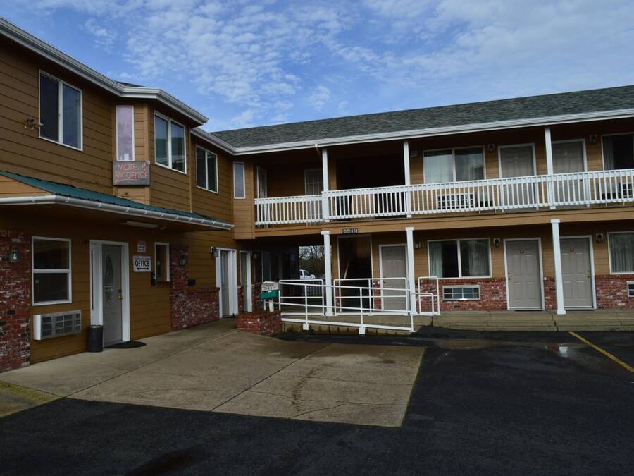A motel with a two-story structure, a covered entrance, and a visible parking area.