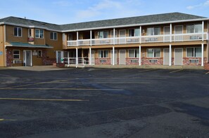 A motel with a two-story structure, a covered parking area, and a fenced entrance. - Western Motel (Junction City)