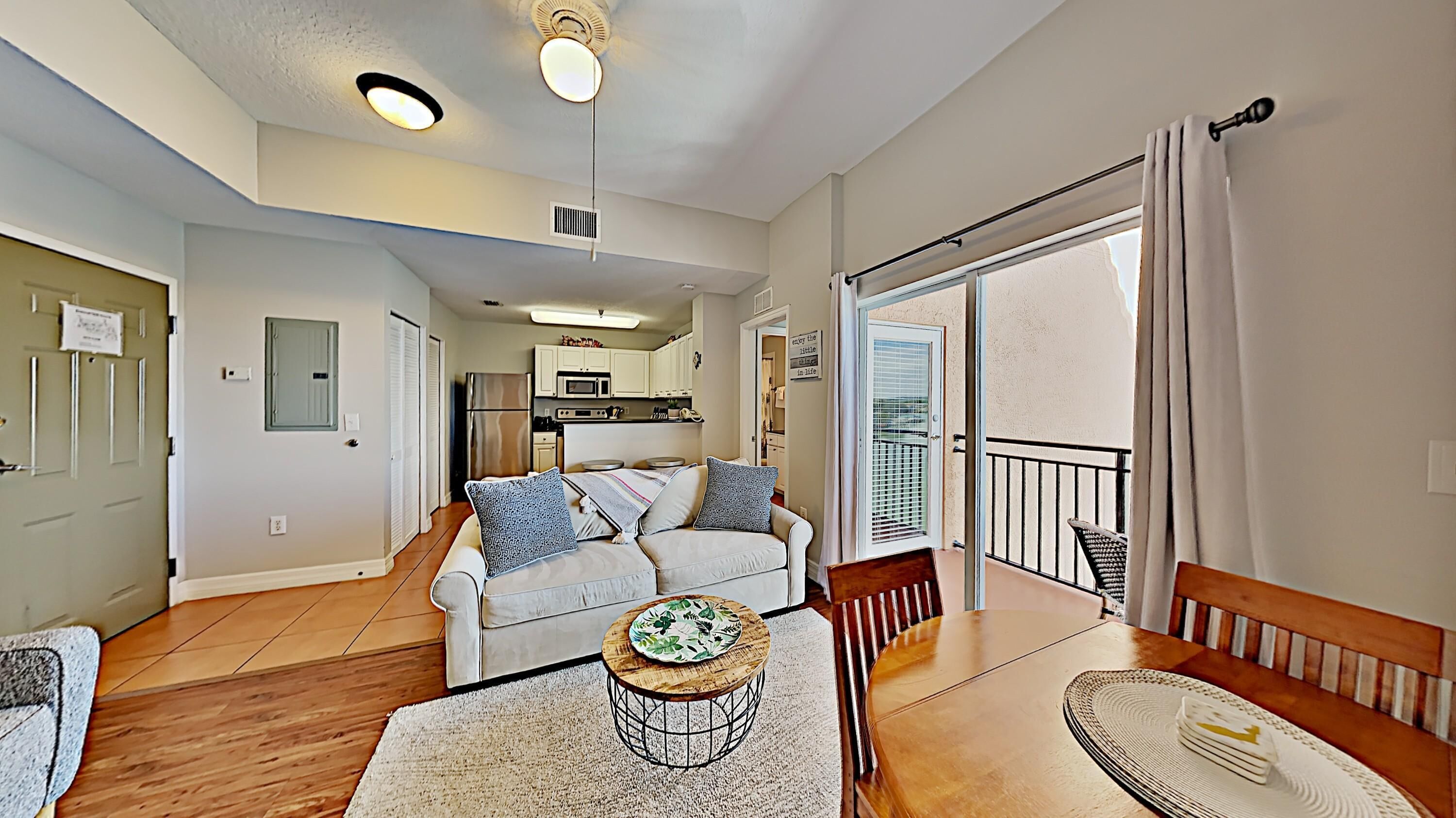 A modern living room with a sofa, a dining table, and a kitchen in the background.