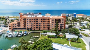 Un hotel de varios pisos con balcones, un puerto deportivo con barcos y vistas al océano.