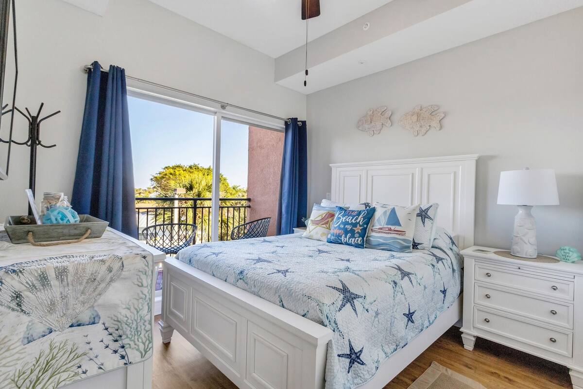 Une chambre à coucher avec un lit, une table de chevet, une chaise et une fenêtre avec des rideaux.