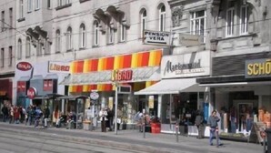 Vista da rua com diversas lojas, incluindo a placa visível 'Pension Vera'.