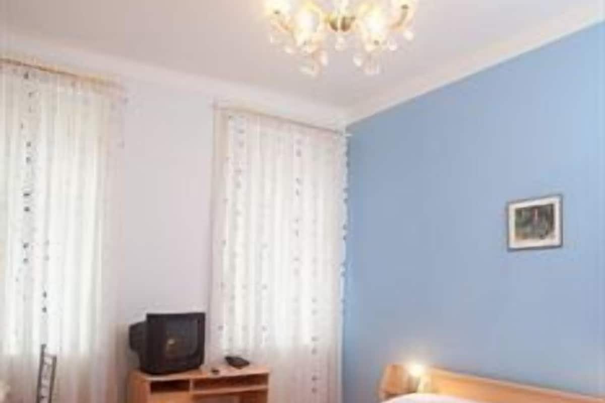 Um quarto com uma cama de madeira, uma escrivaninha com televisão e um candelabro.