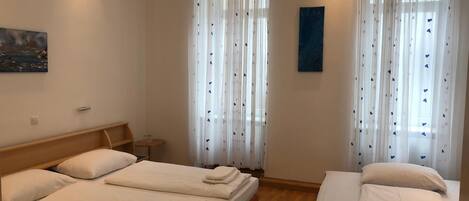 Habitación de hotel con dos camas, una mesita y un cuadro en la pared.