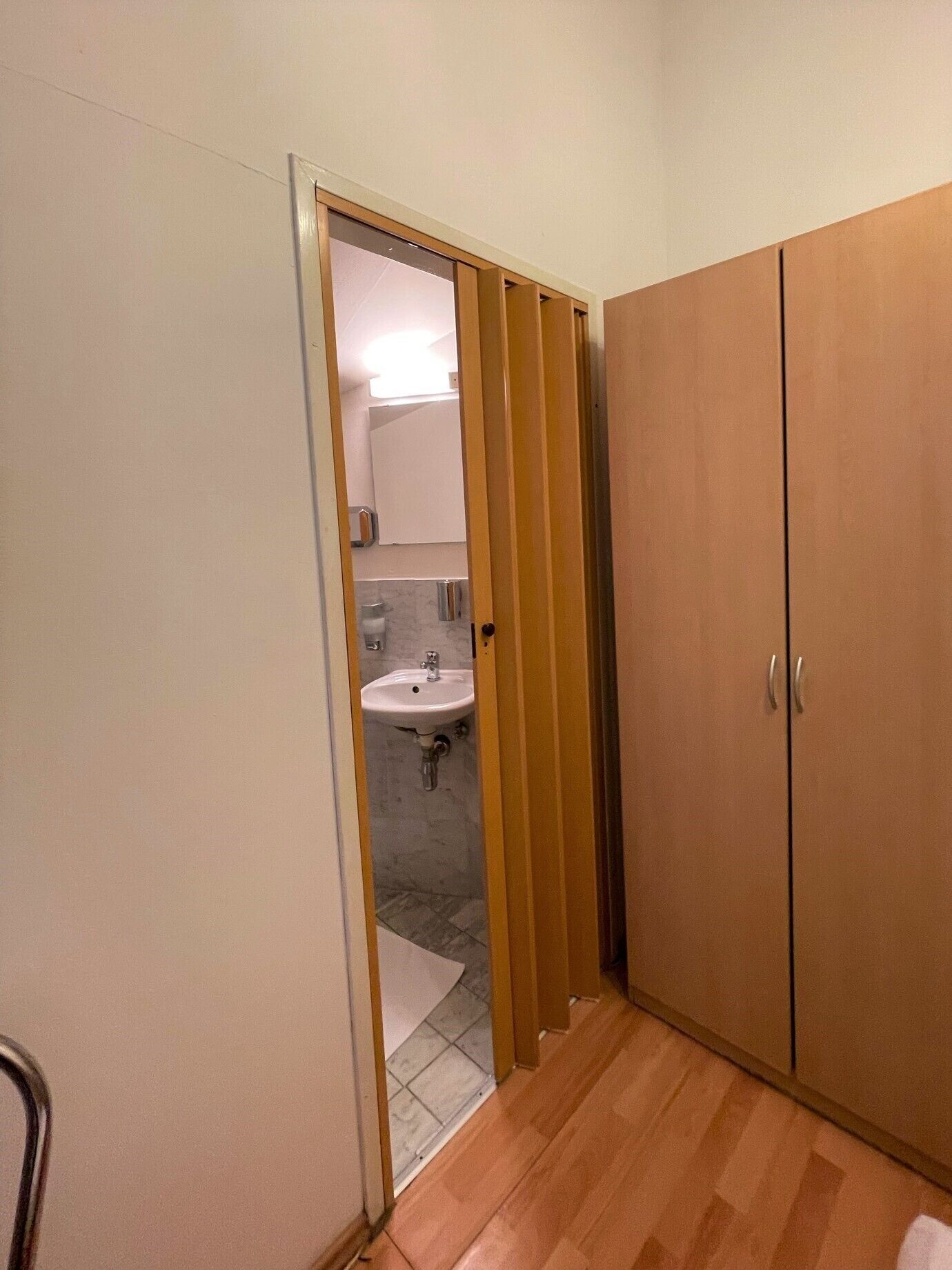 A bathroom with a wooden wardrobe, a sink, and a mirror.