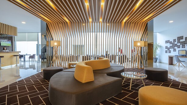 Um lobby moderno com piso de padrão geométrico, disposição de assentos contemporânea e um design de teto singular.