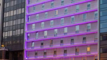 Un hotel moderno con fachada de varios pisos, amplias ventanas y una entrada destacada con un letrero que dice “FENIX URBAN”.