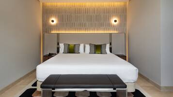 Een moderne hotelkamer met een groot bed, nachtkastjes, een bankje en een kamerbreed tapijt met dessin.
