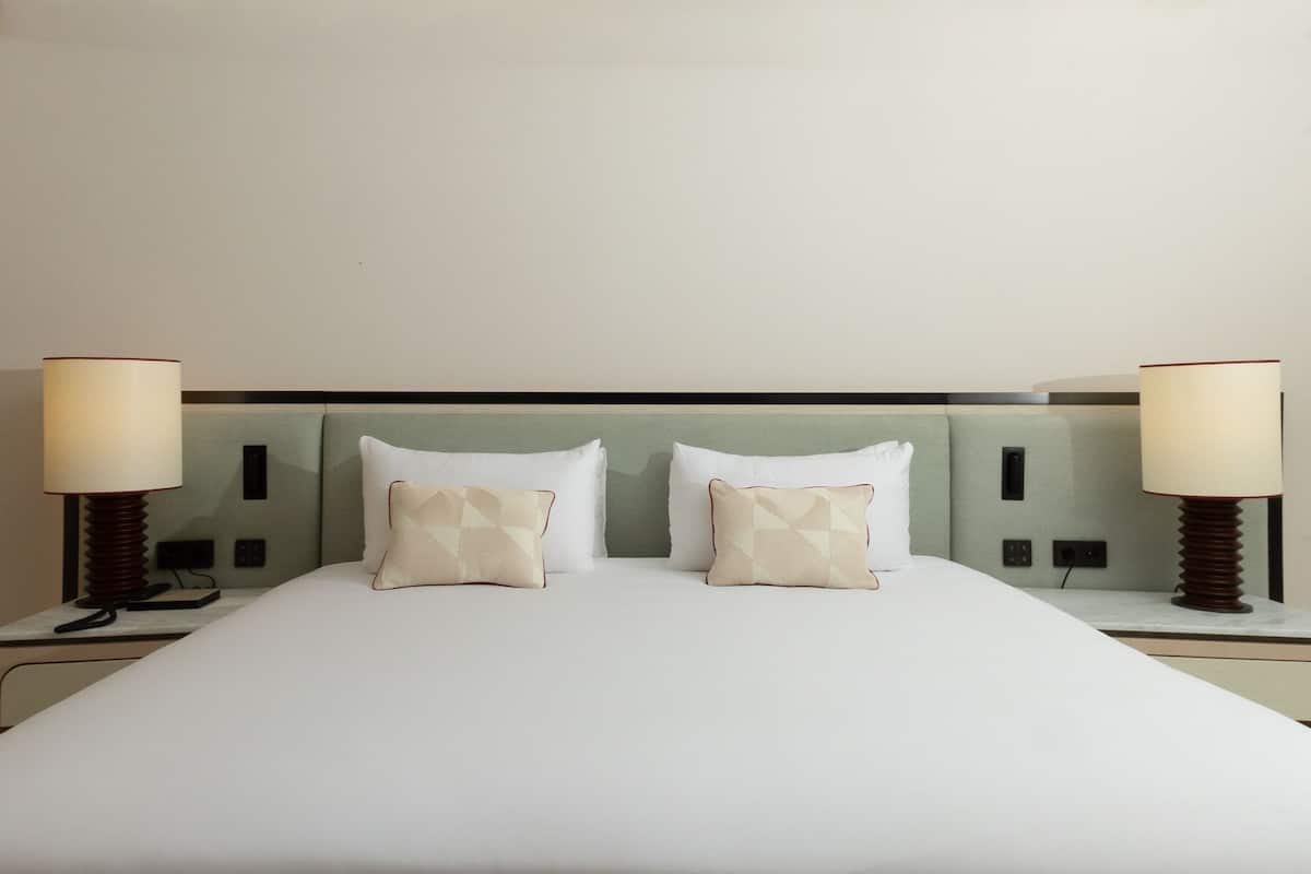 Ein Hotelzimmer mit einem Bett, zwei Nachttischlampen und einem Kopfteil.