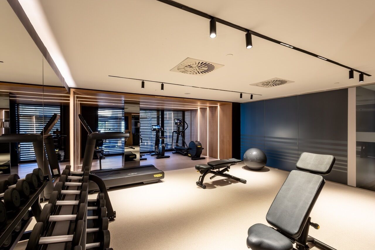 Un gimnasio moderno con equipo de ejercicio, una banca y un espejo grande.