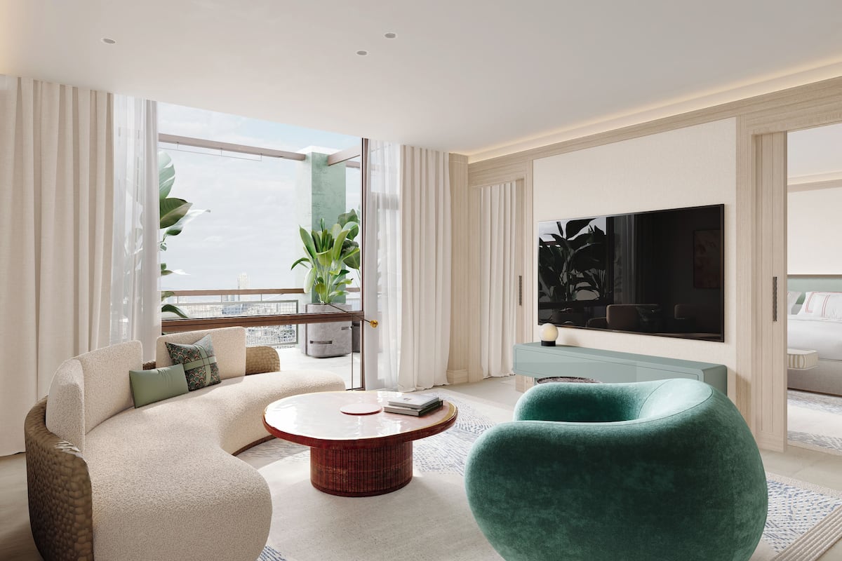 Ein modernes Wohnzimmer mit einer Couch, einem runden Couchtisch und einem grünen Sessel. An der Wand hängt ein großer Fernseher und es gibt einen Balkon mit einer Pflanze.