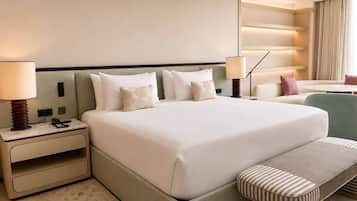 A hotel room with a large bed, bedside tables, a desk, a chair, and a small table.