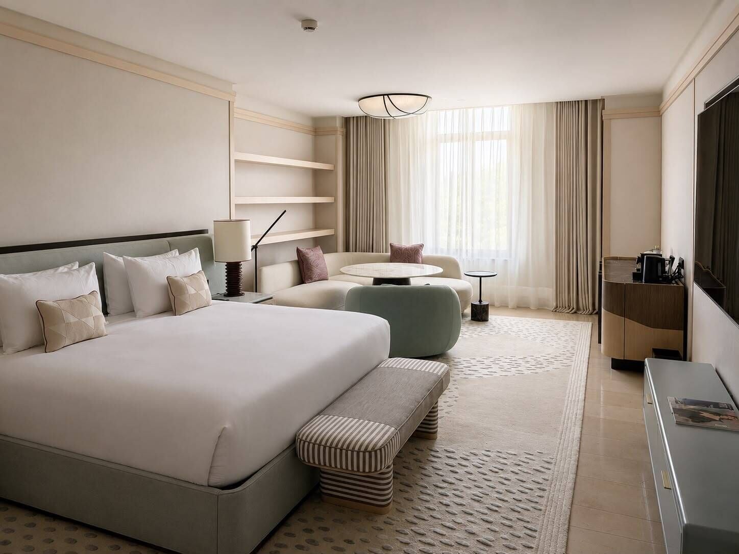 Une chambre d’hôtel avec un grand lit, un canapé, une petite table ronde, un bureau et une télévision.