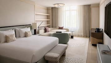 Une chambre d’hôtel avec un grand lit, un canapé, une petite table ronde, un bureau et une télévision.
