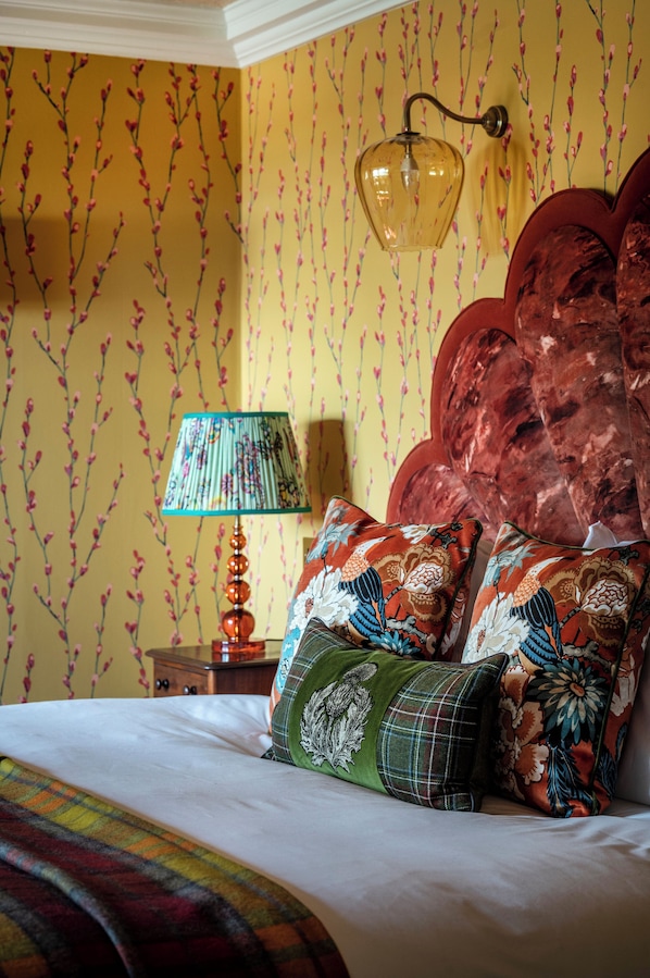 A bedroom with a bed, pillows, a lamp, and a wall with floral wallpaper. - The Glenmorangie House (Tain)