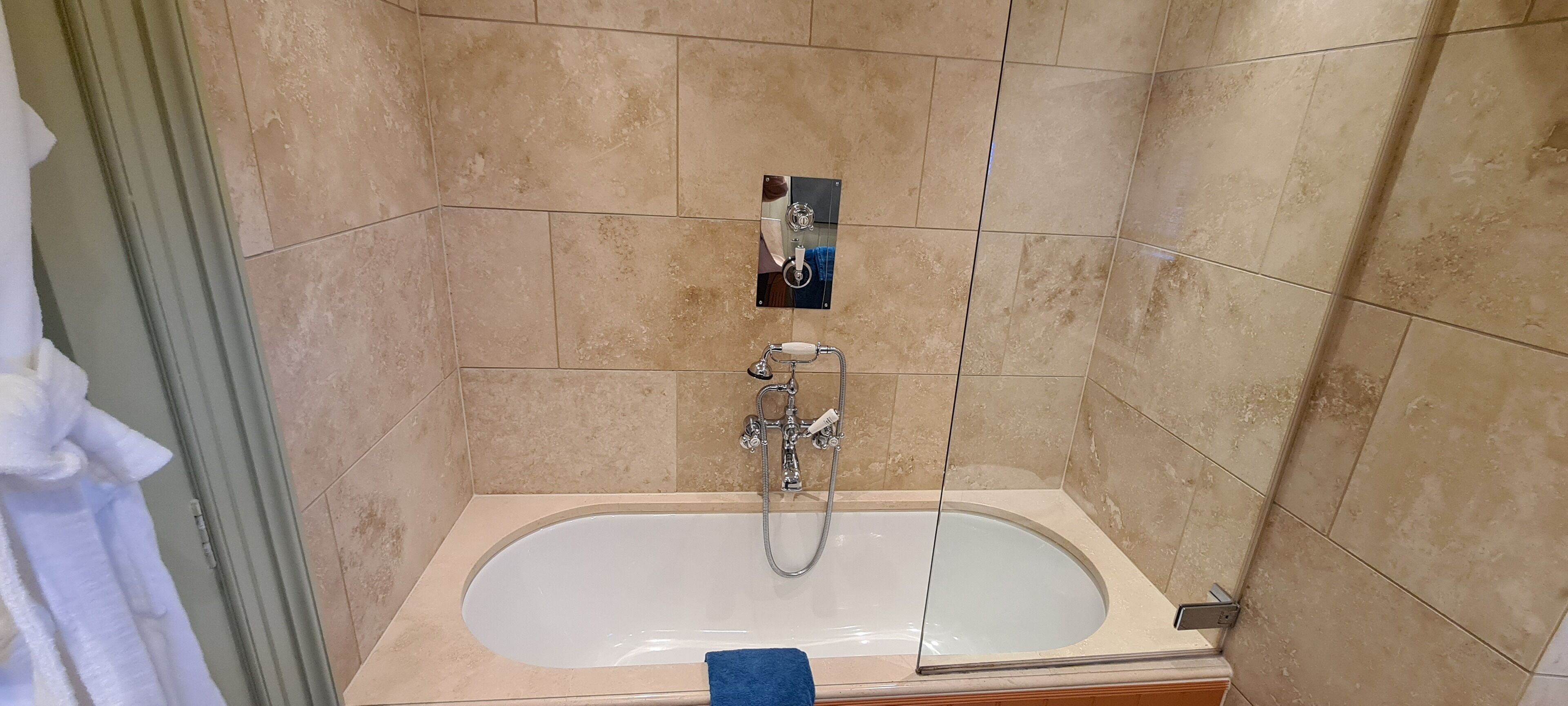 Ett badrum med badkar, dusch och handduksställ.