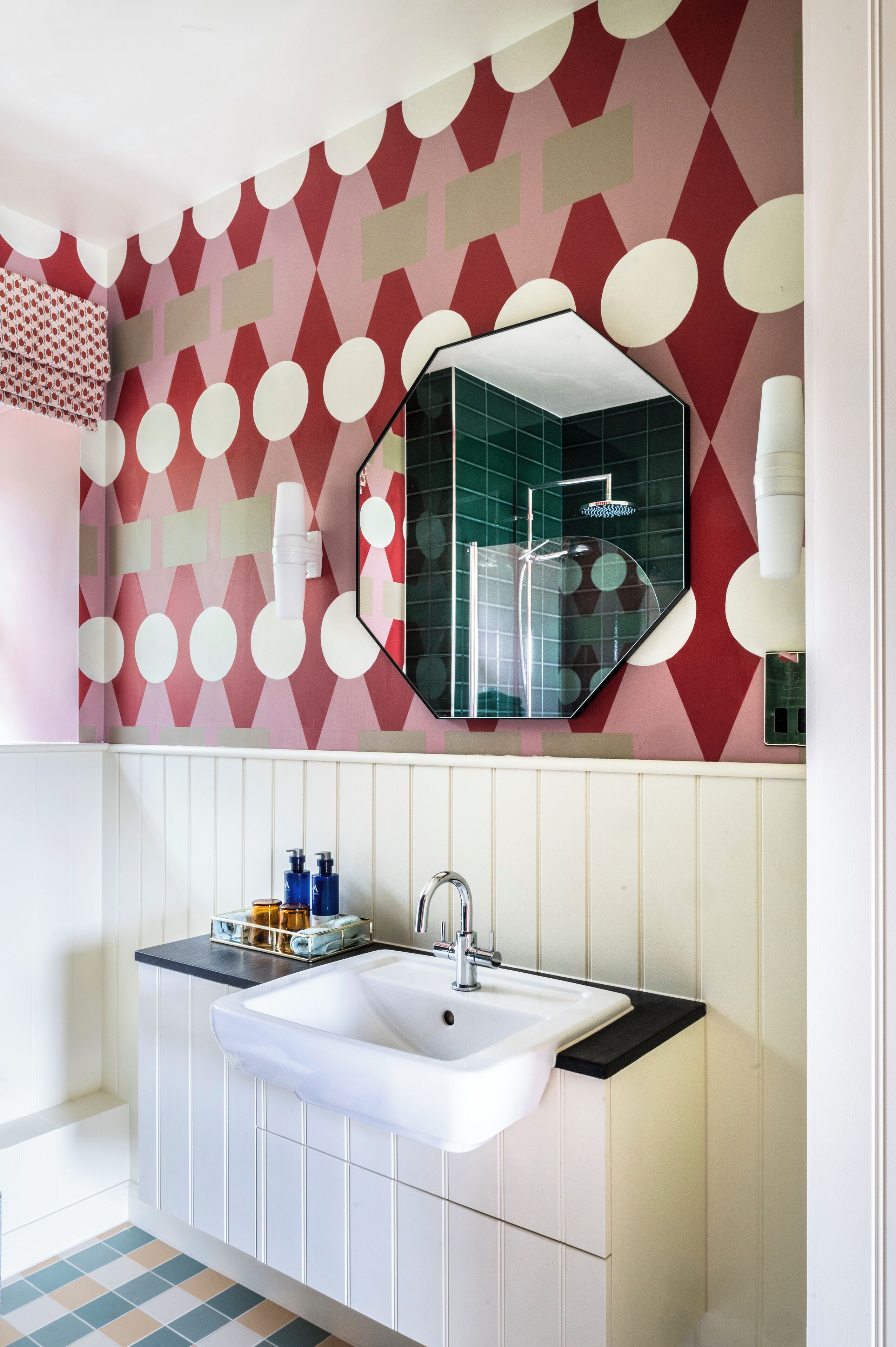 Un baño con lavamanos blanco, un espejo y pared con diseño.