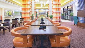 Un salón de conferencias con una larga mesa, varias sillas y una pantalla grande al frente.