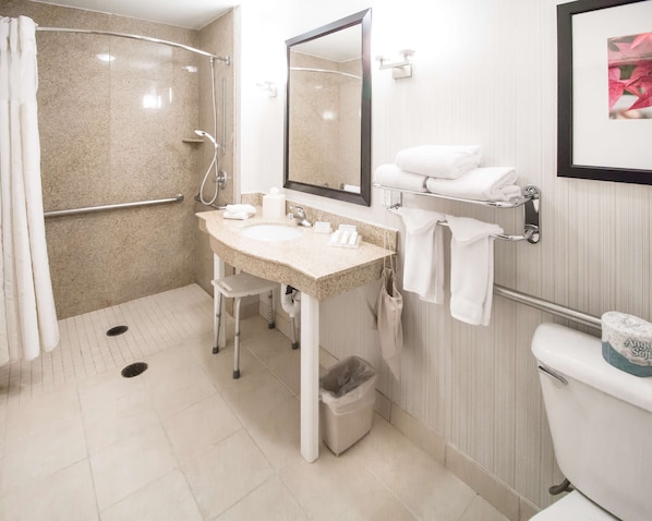 Un baño moderno con ducha, lavamanos, inodoro y secador de manos.