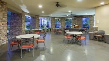 Un vaste patio intérieur doté de murs en pierre, de nombreuses tables et chaises, ainsi que d’une cheminée.