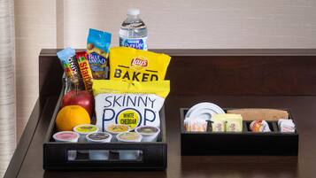 Una bandeja con aperitivos y condimentos, incluyendo papas fritas Lay's Baked, palomitas Skinny Pop sabor cheddar y una botella de agua.