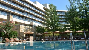 A hotel pool area with sun loungers and umbrellas, surrounded by a multi-story building with balconies. - The Umstead Hotel and Spa (Cary)