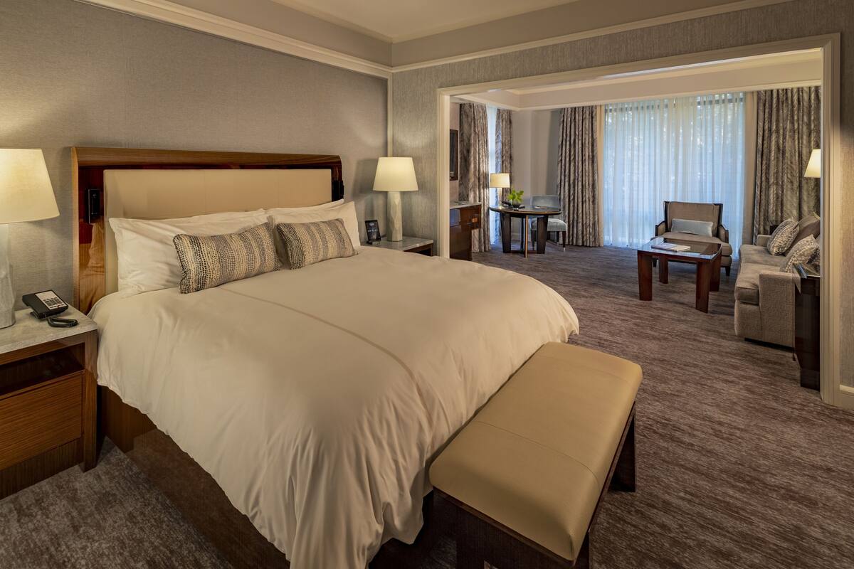 A hotel room with a large bed, bedside tables, a desk, and a chair.