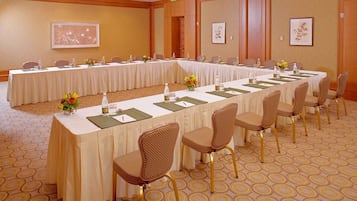A conference room with a long table, chairs, and floral centerpieces.