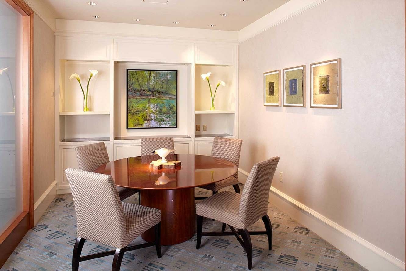Un coin repas avec une table ronde, quatre chaises et un tableau accroché au mur.