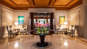 A lobby with a central round table surrounded by armchairs, a chandelier, and a floral arrangement. - The Umstead Hotel and Spa (Cary)