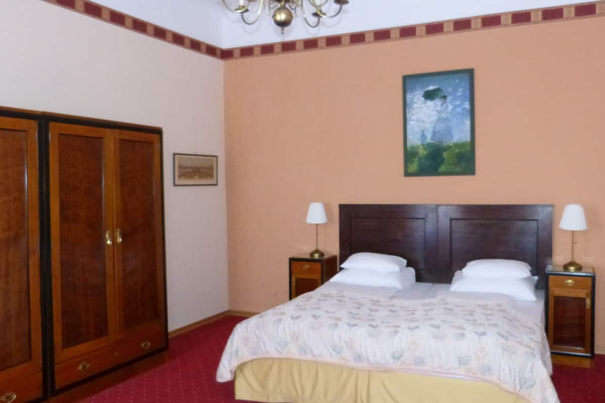 A bedroom with a bed, two bedside tables, a nightstand, a wardrobe, and a painting on the wall.