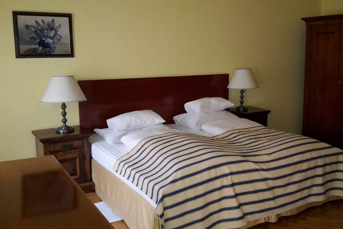 A neatly made bed with a striped blanket, two bedside lamps, and a wooden headboard.