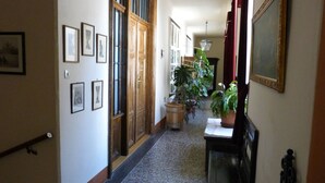 Un couloir orné de tableaux encadrés, une porte en bois portant le numéro 22 et une plante en pot placée au centre.