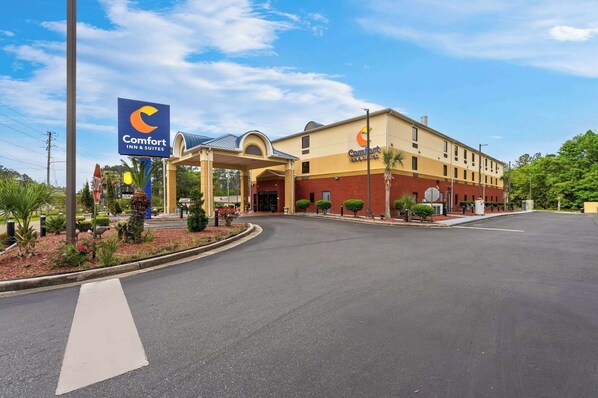 A Comfort Inn & Suites with a covered entrance, a parking lot, and landscaped areas with small trees and shrubs.