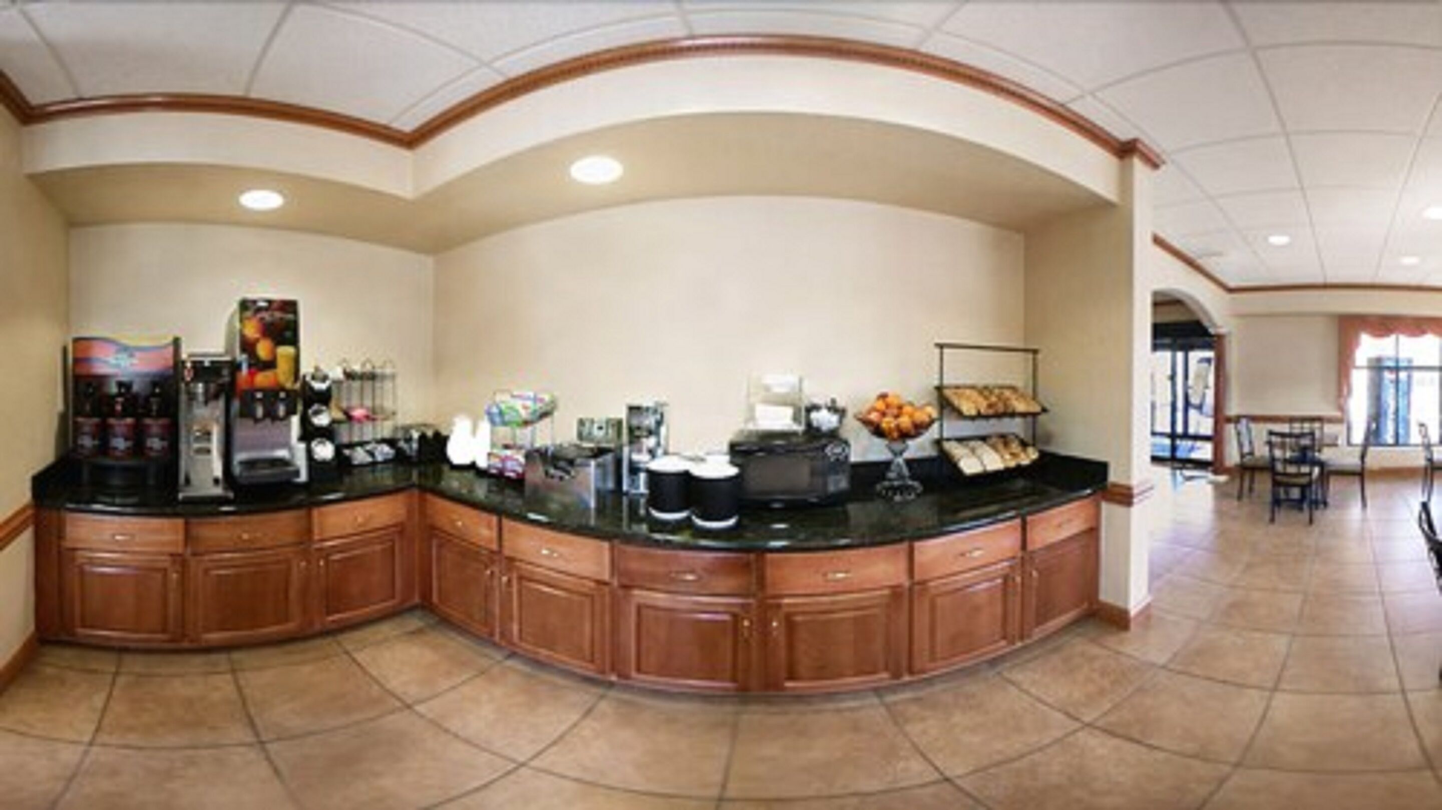 A large breakfast bar with a coffee machine, fruit display, and a bread rack.