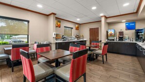 A restaurant with booths and tables, a kitchen area, and a large window. - Comfort Inn & Suites Chipley (Chipley)