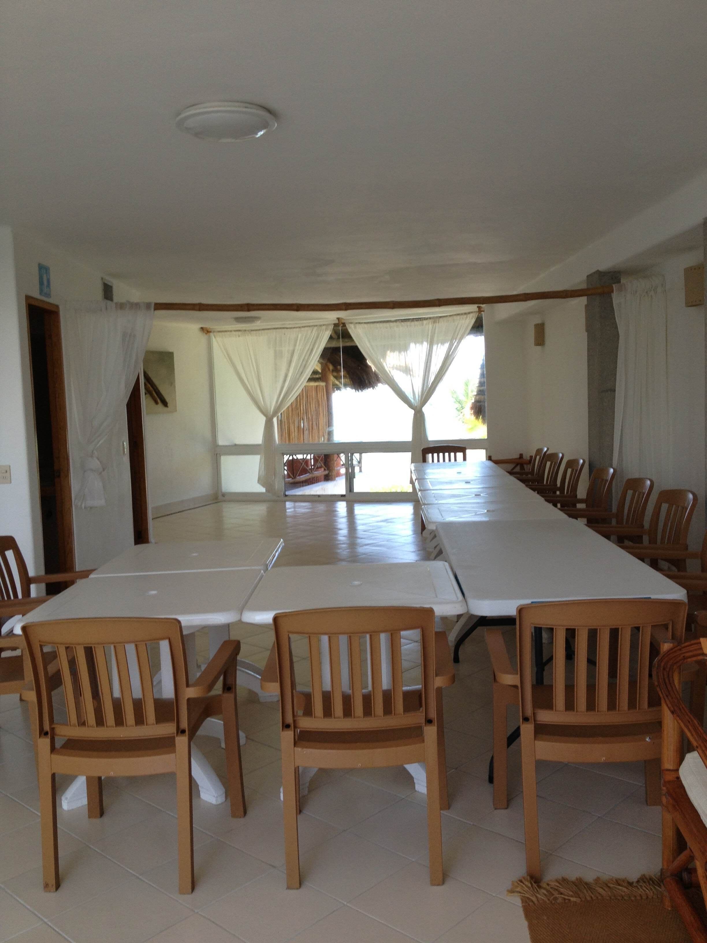 A large conference room with a long table and multiple wooden chairs.