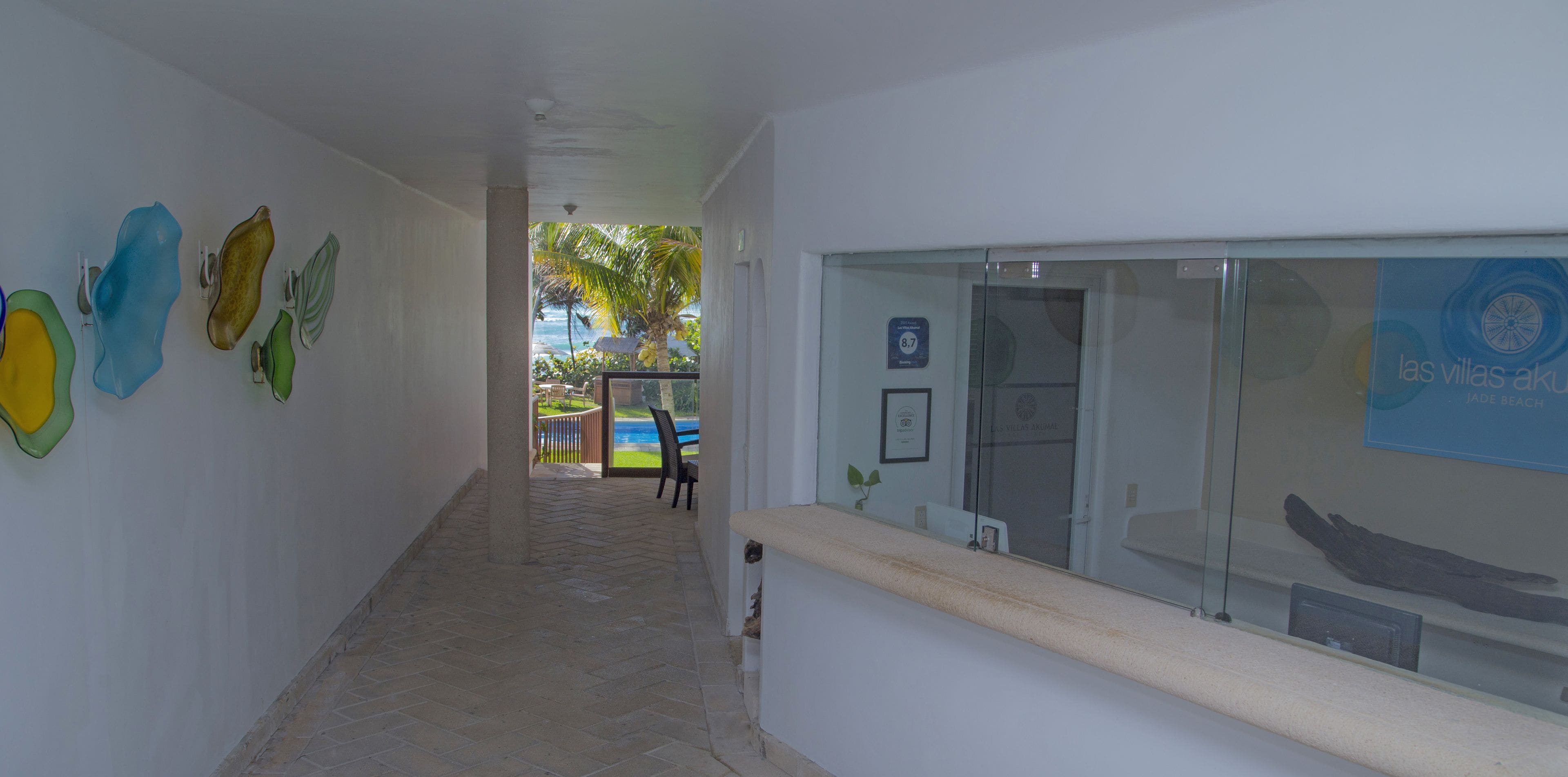 A corridor with a tiled floor, a reception desk, and a glass door leading outside.
