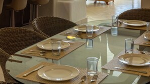 A dining area with a glass table, wicker chairs, and a view of the ocean. - Las Villas Akumal (Akumal)