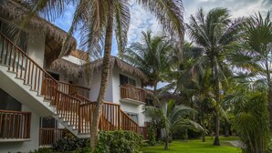 A resort with multiple-story buildings, a thatched-roof structure, and a well-maintained garden with palm trees. - Las Villas Akumal (Akumal)
