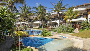 Un resort con varias piscinas, palmeras y un jardín bien cuidado.