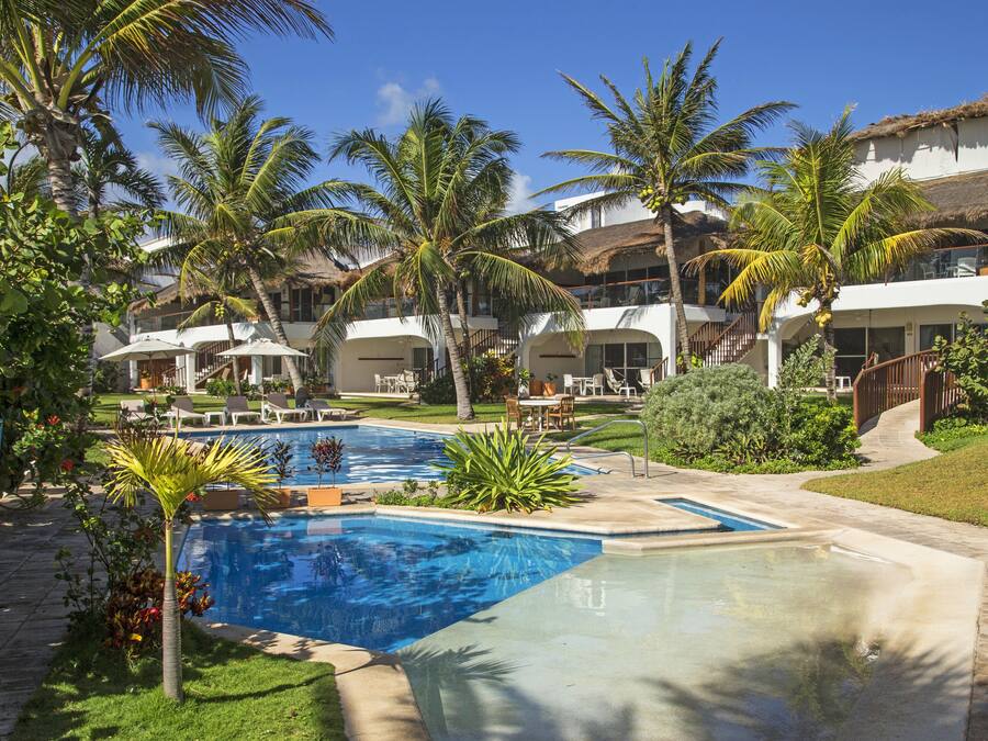 Un resort con varias piscinas, palmeras y un jardín bien cuidado.