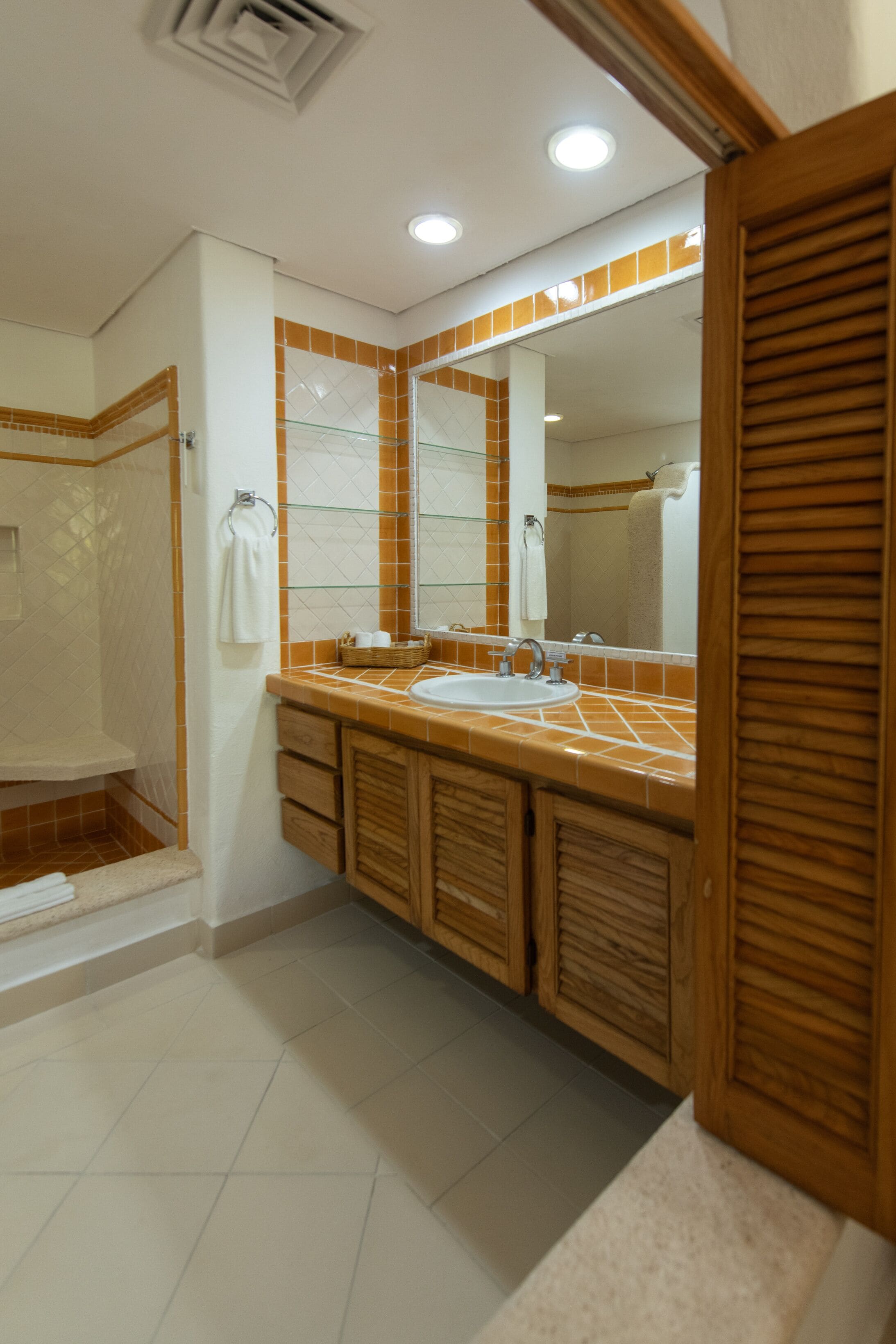 Un bagno con un mobile lavabo in legno, un lavandino e uno spazio doccia.