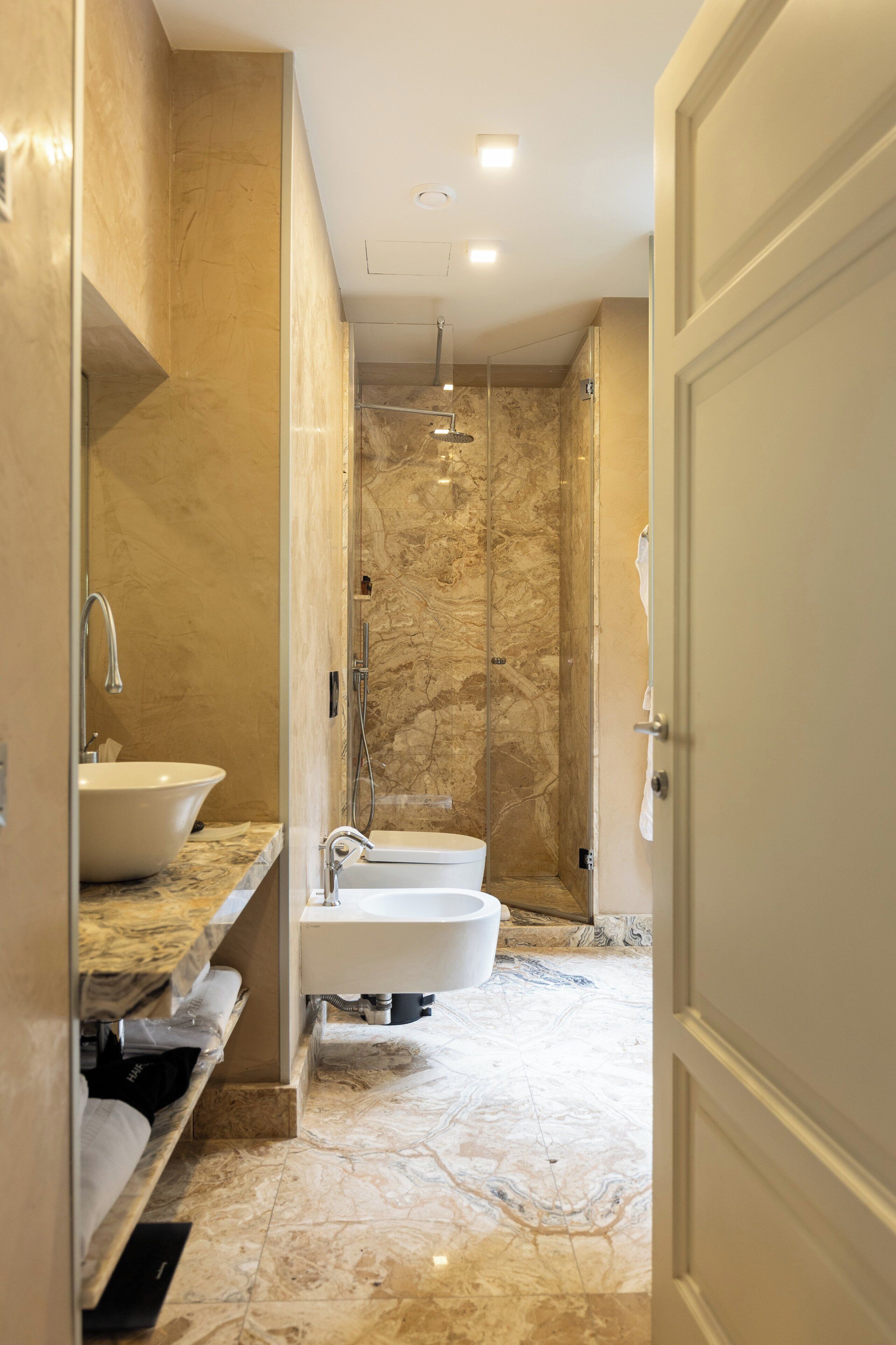 A modern bathroom with a marble floor, a freestanding bathtub, and a shower enclosure.