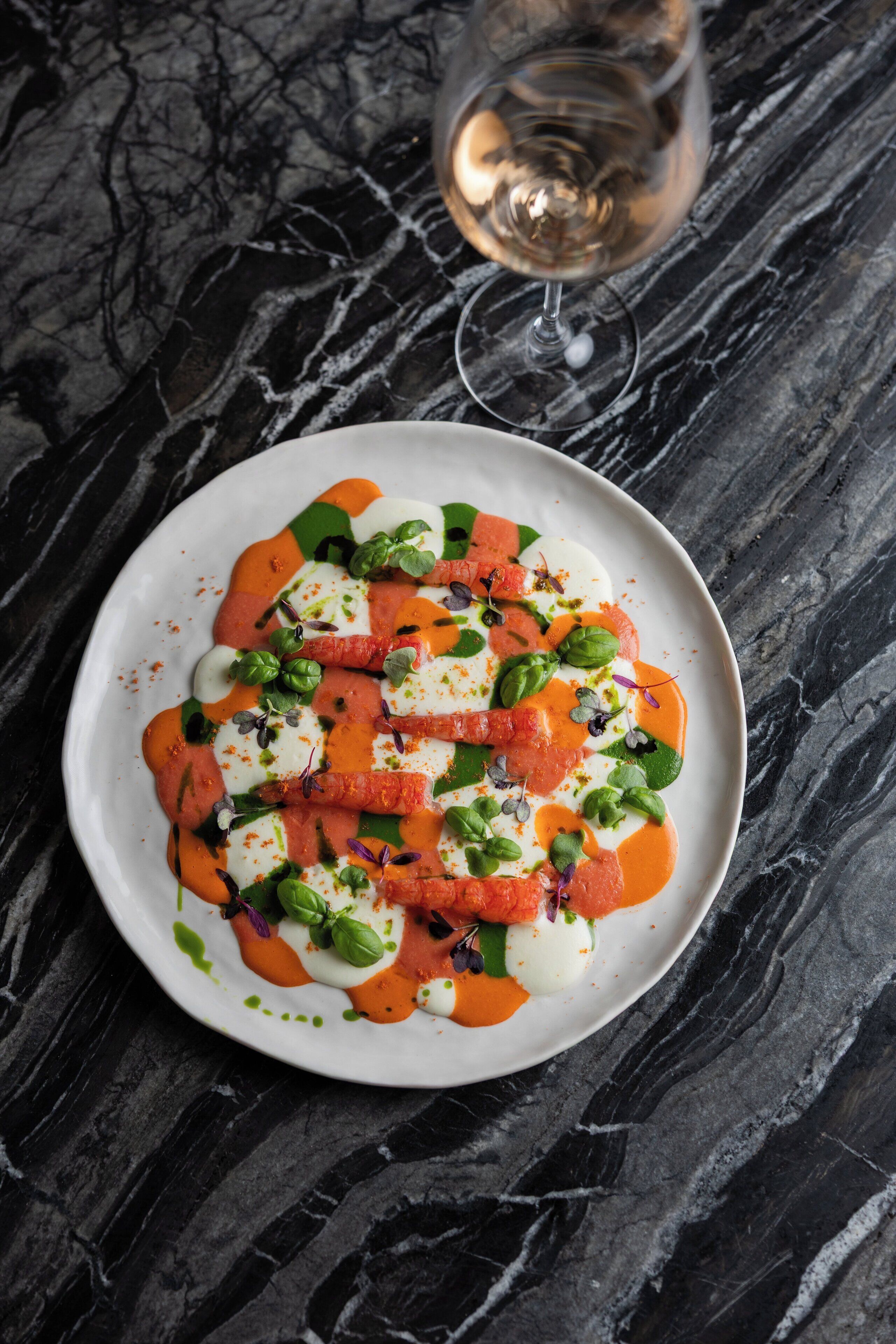 A white plate with a salad on a dark marble surface.