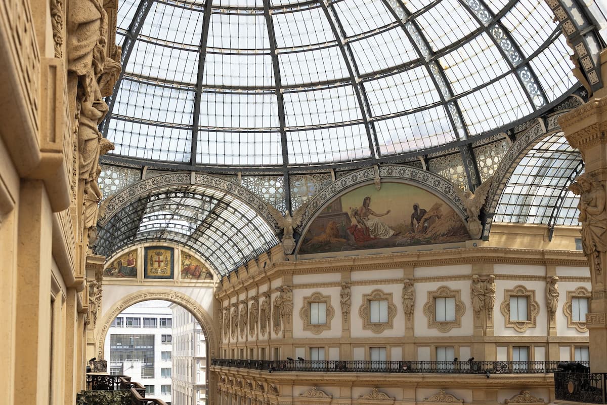 Un vaste atrium doté d’une haute verrière, de colonnes richement décorées et d’un espace central ouvert où se trouvent des boutiques.