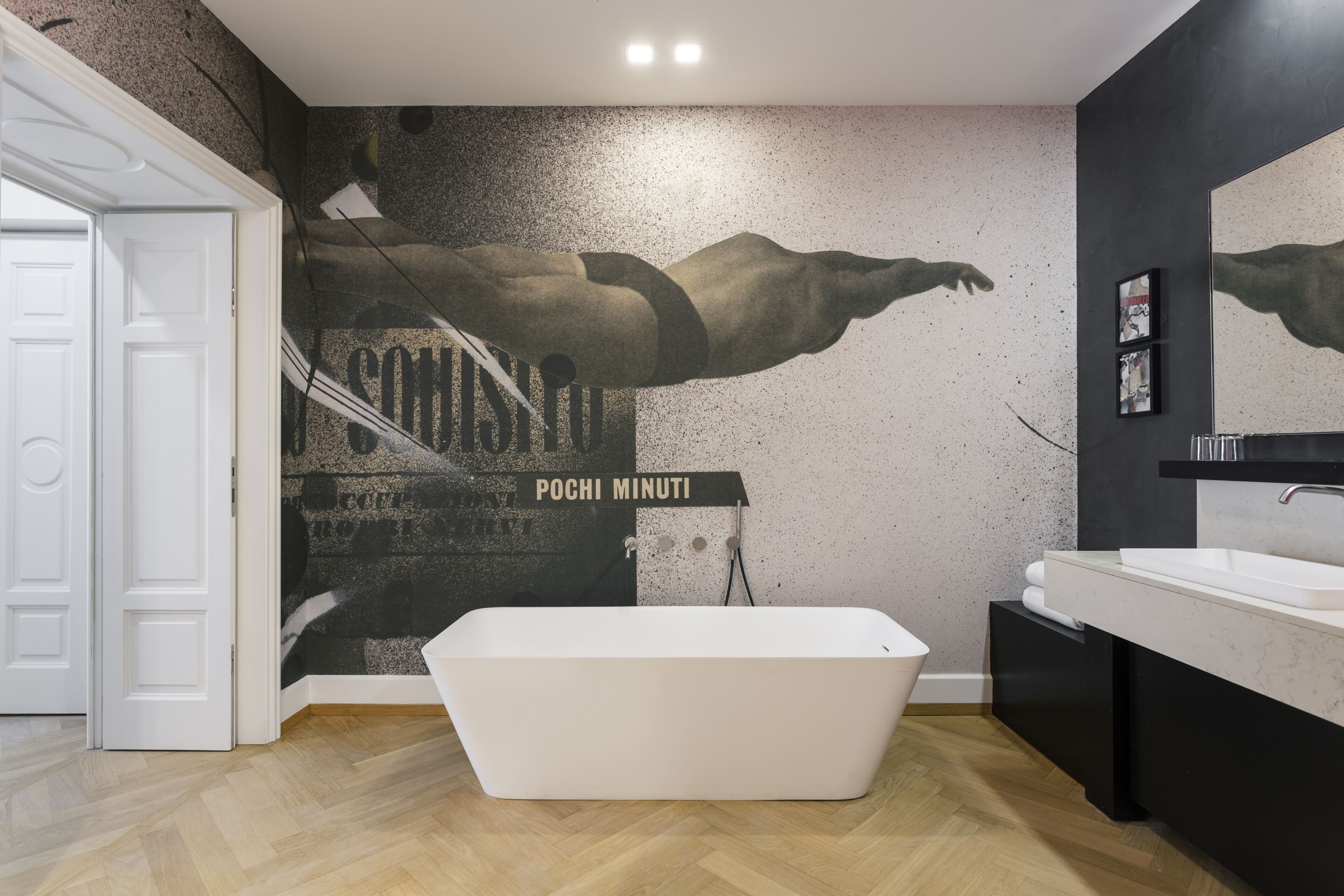 A modern bathroom with a freestanding bathtub, a large mirror, and a wall mural.
