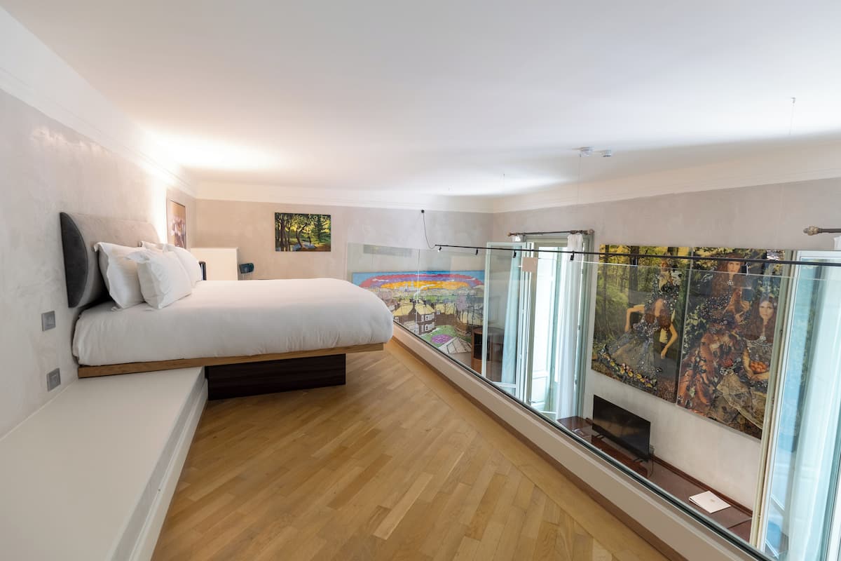 Une chambre moderne avec un lit, un balcon en verre et une vue sur la ville.